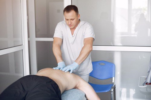 Sciatica Treatment with a healthcare professional performing a lower back massage on a patient lying face down on a treatment table