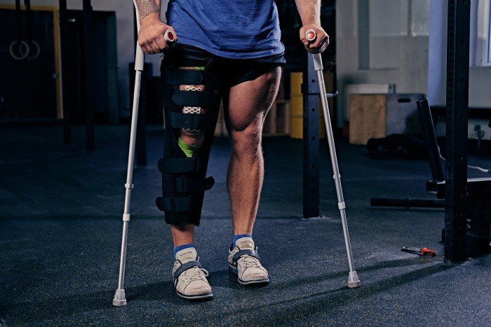 Person using crutches with a knee brace on an injured leg, related to Fracture Surgery